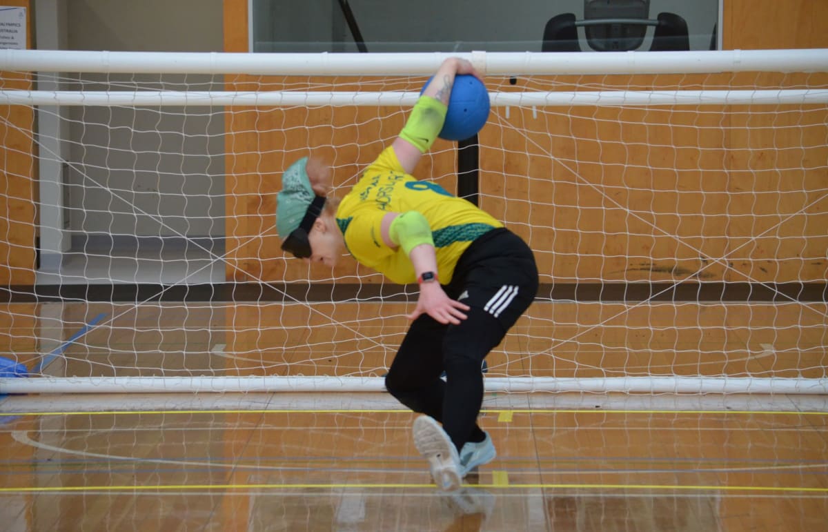 Image of Meica Horsburgh in her Australian Goalball uniform, preparing to throw the ball on goalball court.