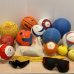 Image of a range of audible Blind Sports Balls, eye shades and running tethers on a table.