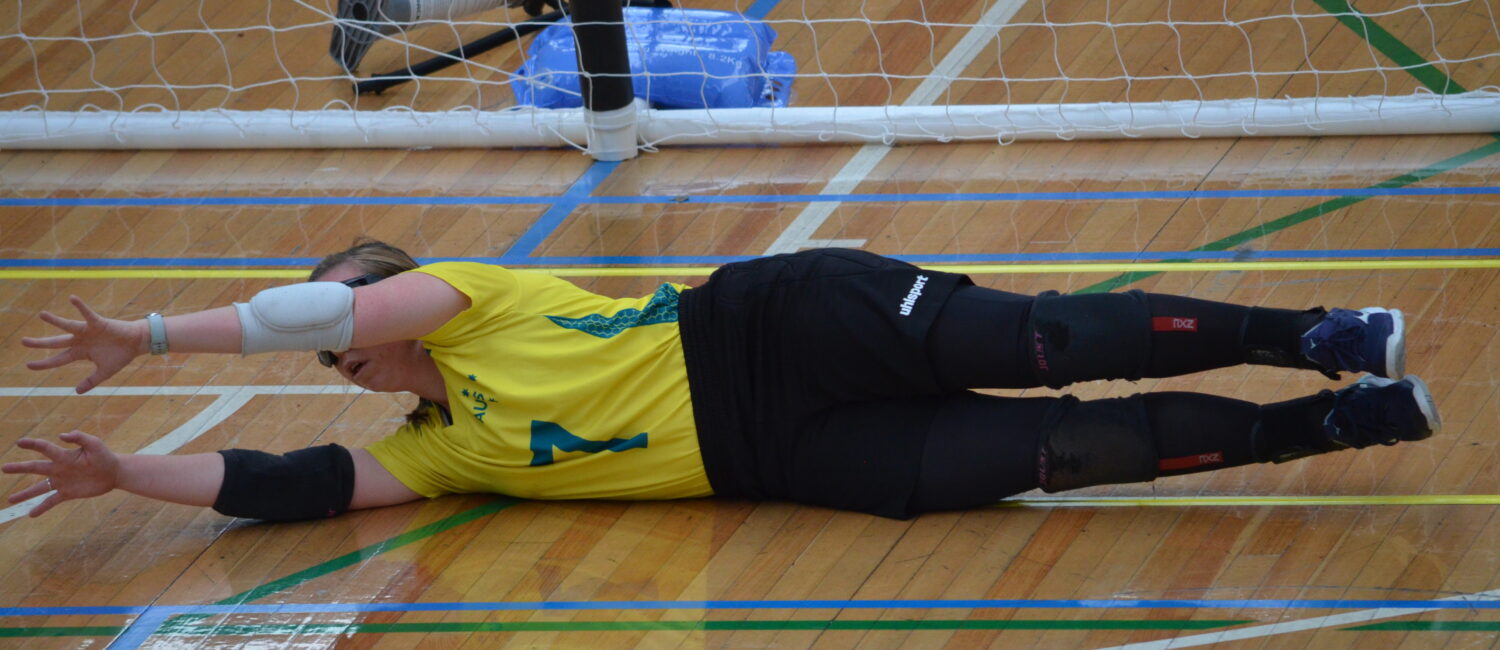 Image of Raissa Martin, in her Australian Womens Goalball Team uniform, diving to save a ball on court