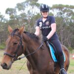 Young woman on top of horse smiling at the camera