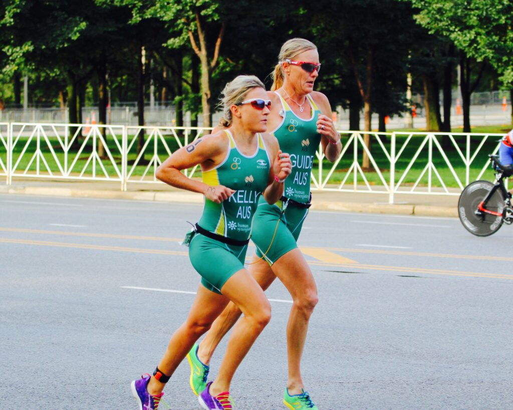 Australian Para-Triathlete Katie Kelly running along side her guide on the road.