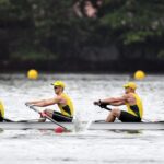 4 rowers in Australian uniforms, rowing boat on river.