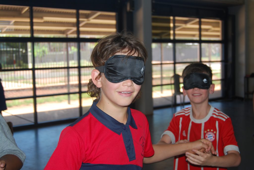 a student wearing a blind fold looking at the camera smiling