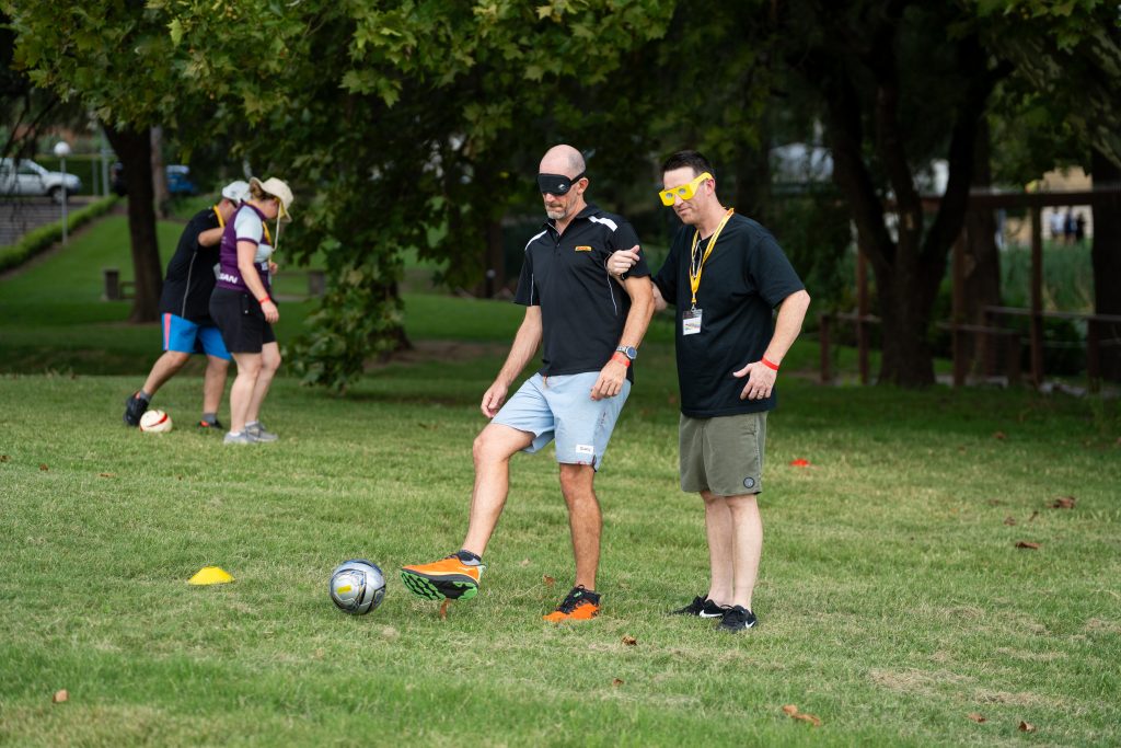 Two participants at a corporate team building program trying Blind Football for the first time