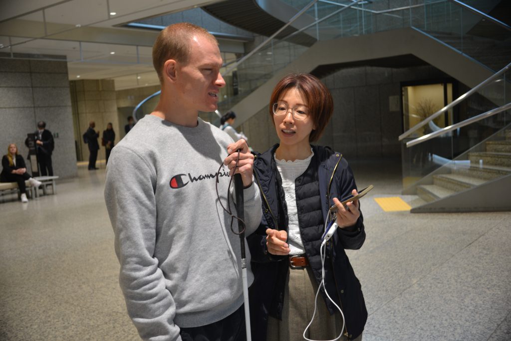 Brendan experiencing a demonstration by Ashirase, Inc. regarding their navigation device for the visually impaired